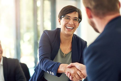 Twee mensen die elkaar de hand schudden in een vergaderruimte.
