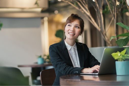 Woman thinking and working on her computer with plants around her