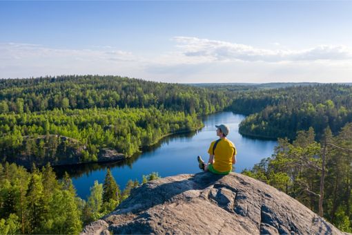 Man sitting on cliff looking at landscape