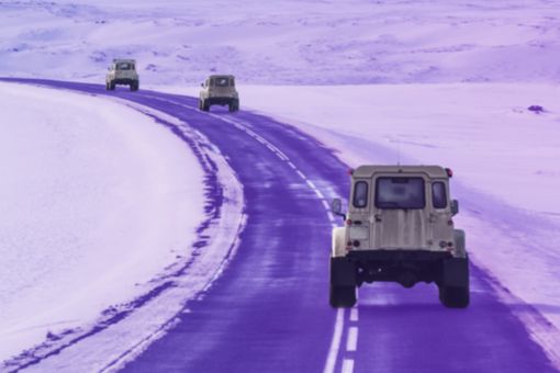 Þrír hvítir jeppar ferðast eftir vegi á Íslandi um vetur