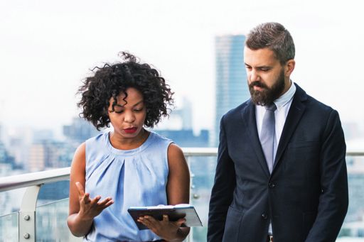 Two businesspeople looking at a tablet, discussing a strategy