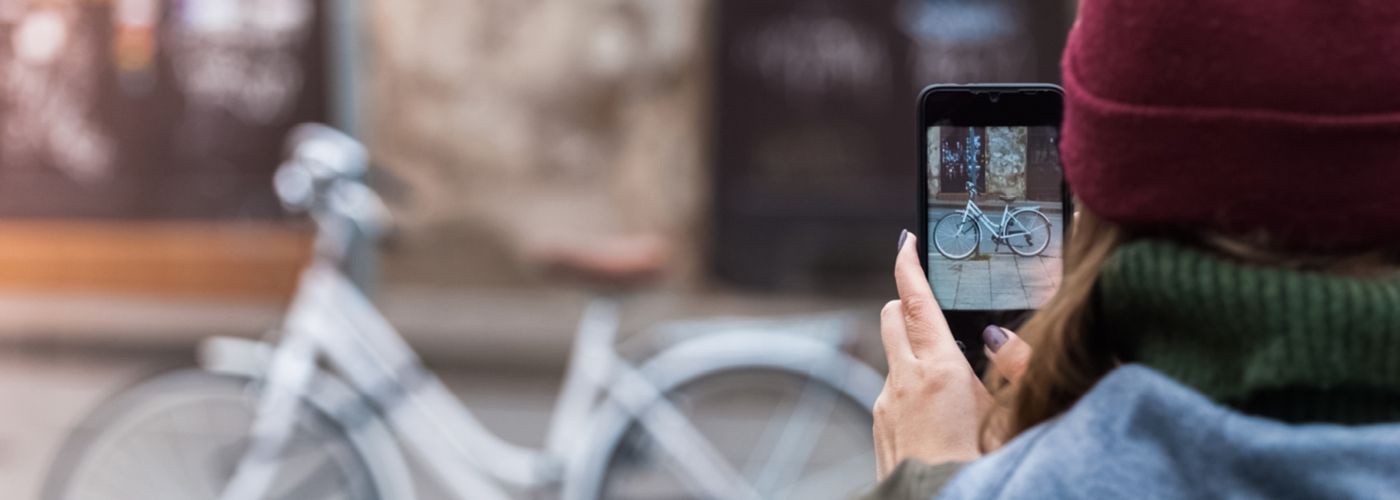 vrouw neemt foto van fiets met haar mobiele telefoon