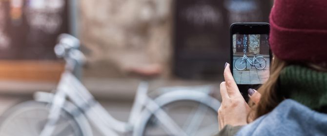 vrouw neemt foto van fiets met haar mobiele telefoon