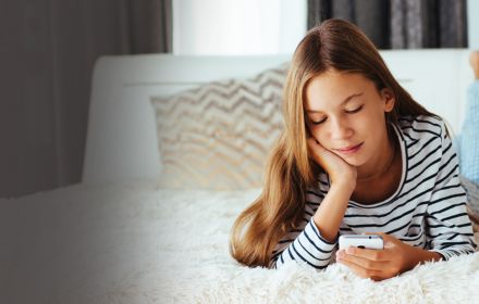 A girl resting on bed while looking at phone