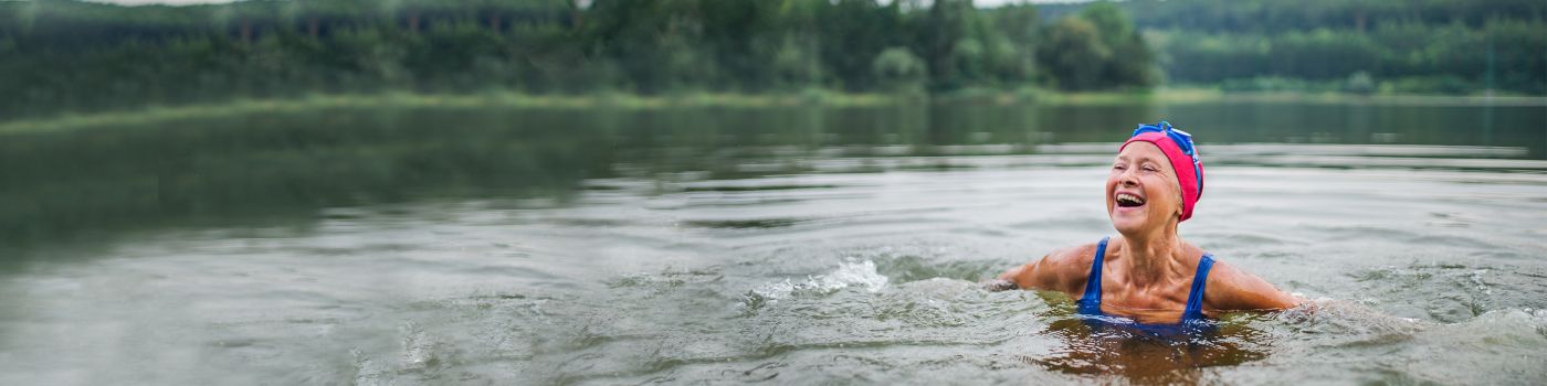 Active senior woman swims in a lake