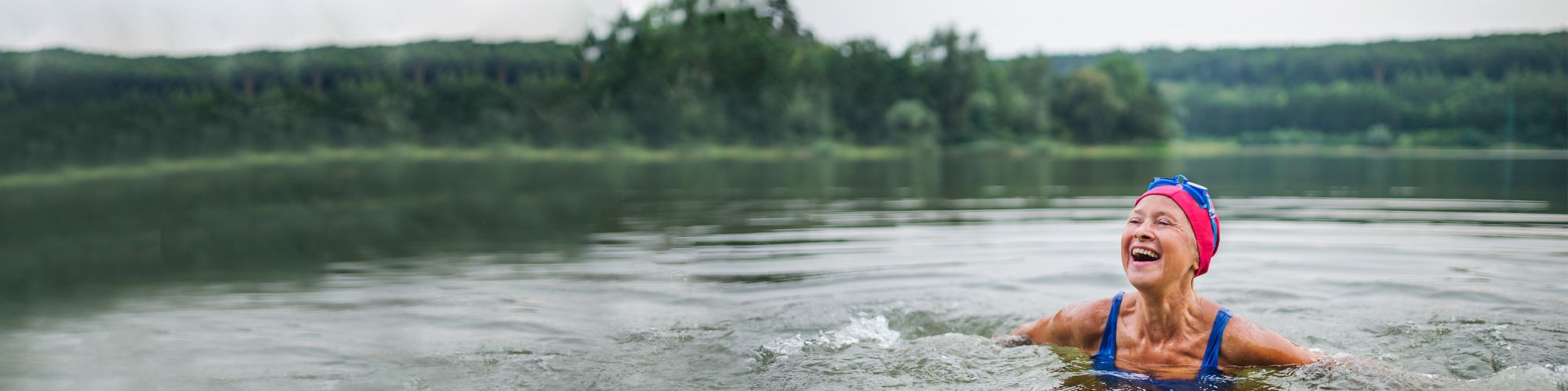 Active senior woman swims in a lake