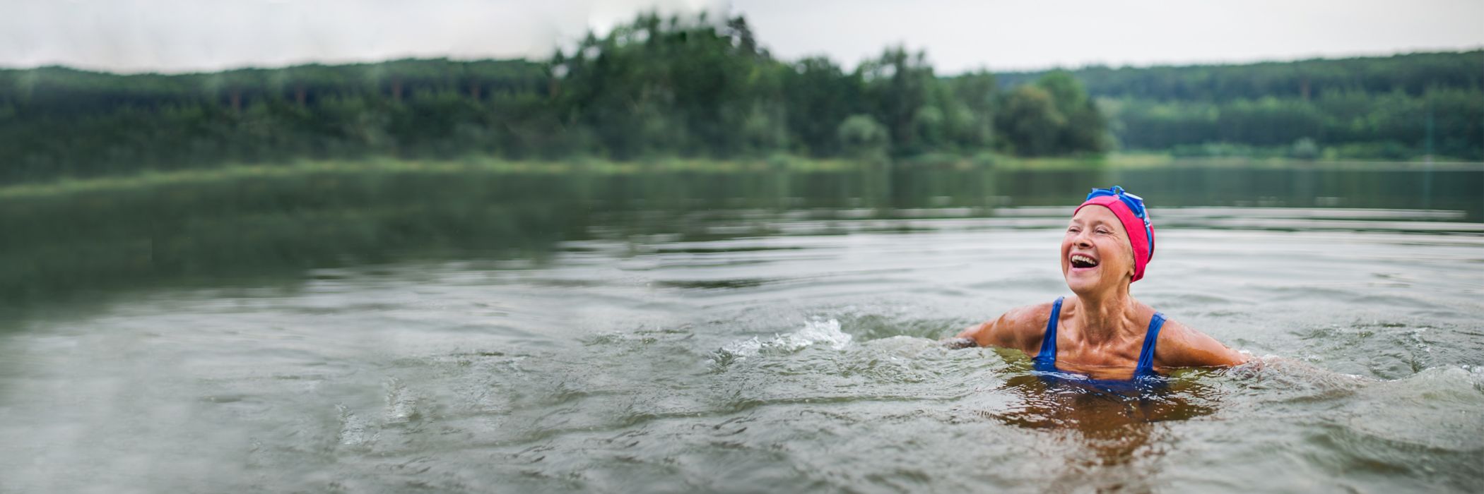 An active senior woman swims in a lake