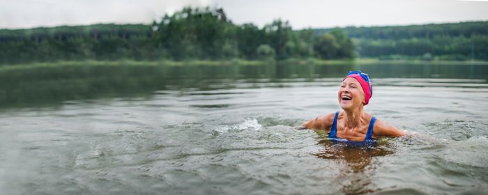 An active senior woman swims in a lake