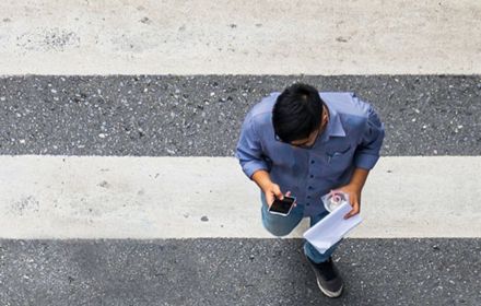 Aerial view of man using cell phone while walking on zebra crossing