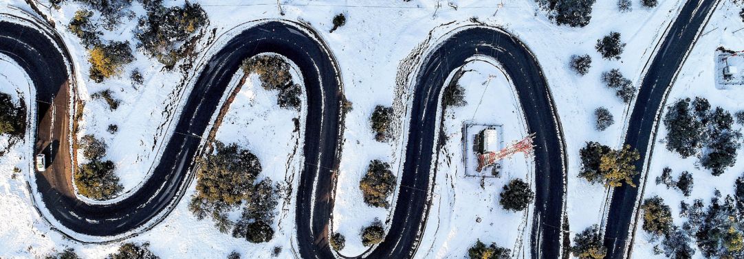 Aerial view of zigzag road covered in snow all around