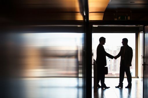 dois executivos apertando mãos em um corredor