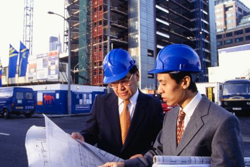 architects discussing blueprint on construction site