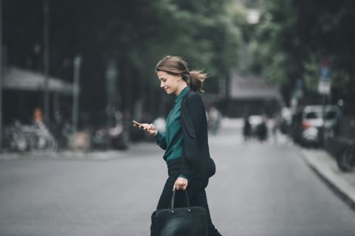 Woman walk in the street with smartphone on hands