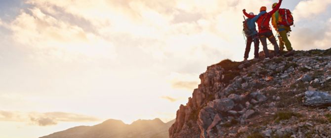 Bergsteiger jubeln im Sonnenuntergang