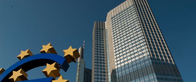 Big blue euro sign with golden stars in front of tall building