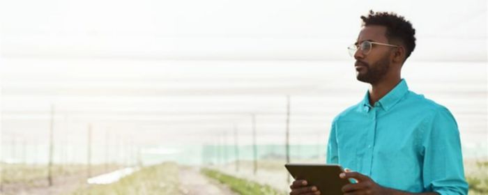 man with a tablet standing in an agricultural field