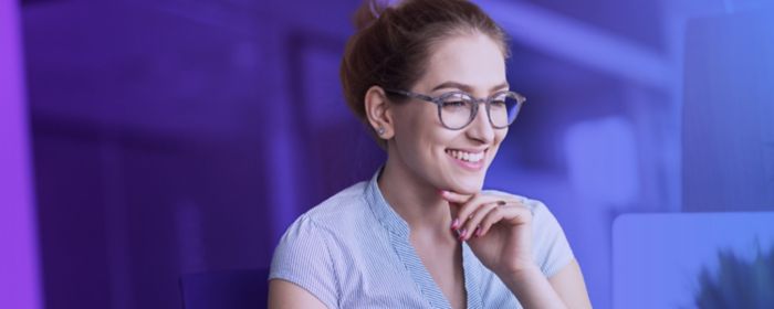 Woman smiling whilst working on a laptop at a desk