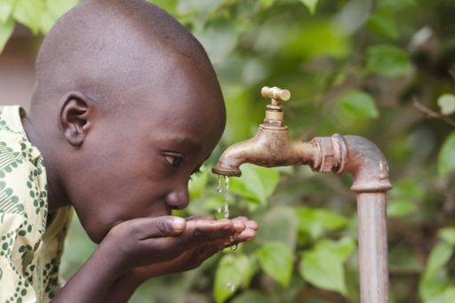Boy drinking water through tap