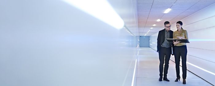 Businesspeople standing in an office corridor looking at a file