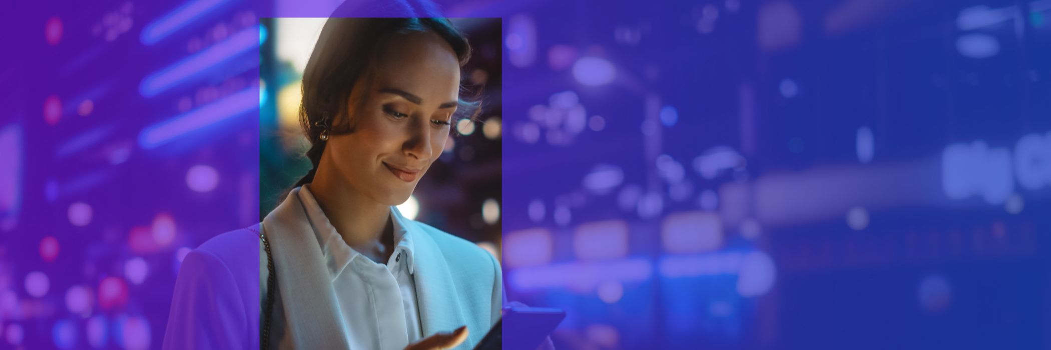 Business woman smiling at phone in the city at night