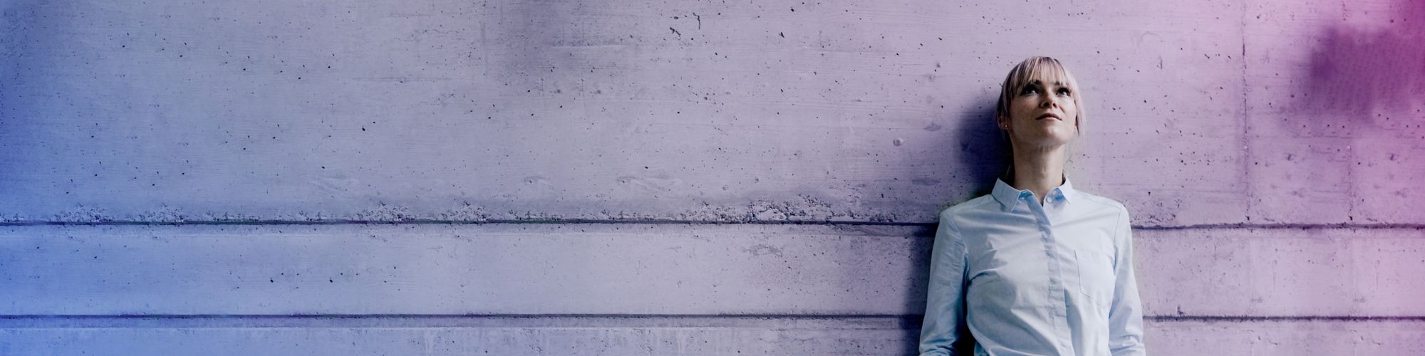 Businesswoman leaning on concrete wall