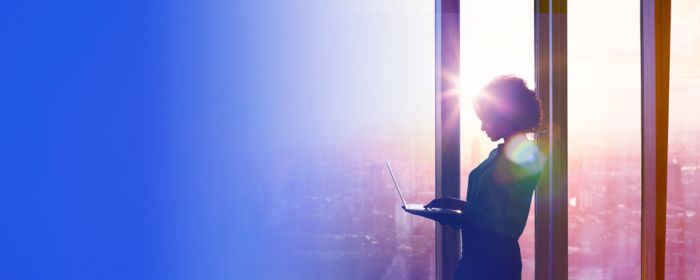 Woman working on laptop at a window in the morning sun