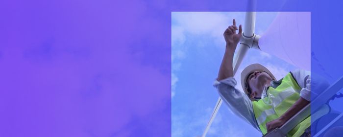 bottom up view of two persons looking at the horizon with wind turbines in background