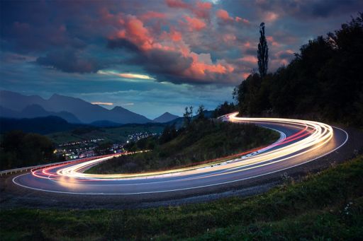 Cars light trails on road with circular turn