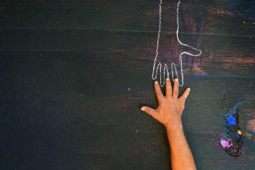 Chalk hand outline with real hand reaching towards it