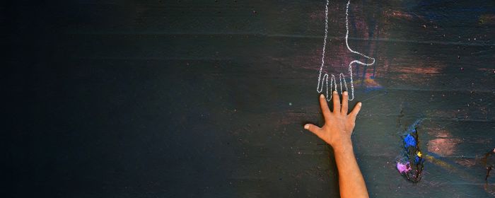 Chalk hand outline with real hand reaching towards it