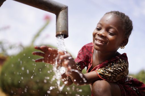 Child washing her hands undera water tap