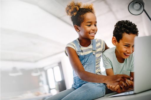 Children using laptop and smiling