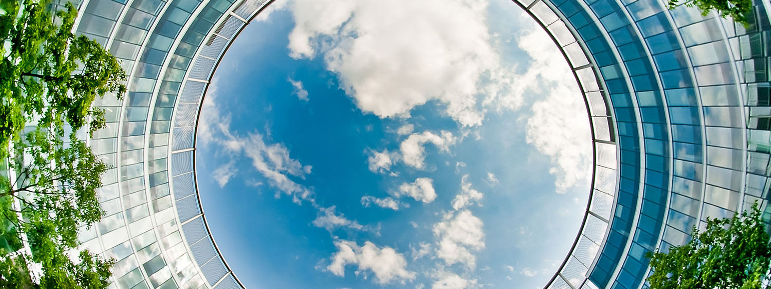 Circular glass building with sky and trees