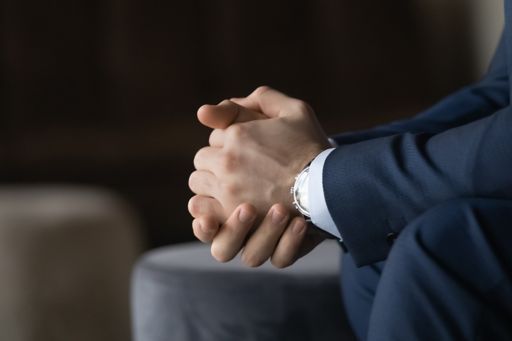 Close up folded male hands, nervous stressed young businessman in suit thinking of difficult problem solution
