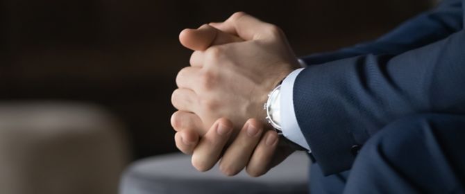 Close-up of businessman resting clasped hands on knees