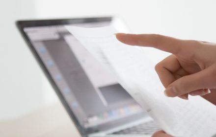 Woman checking paper vs laptop