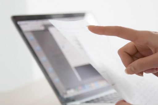 Woman checking paper vs laptop