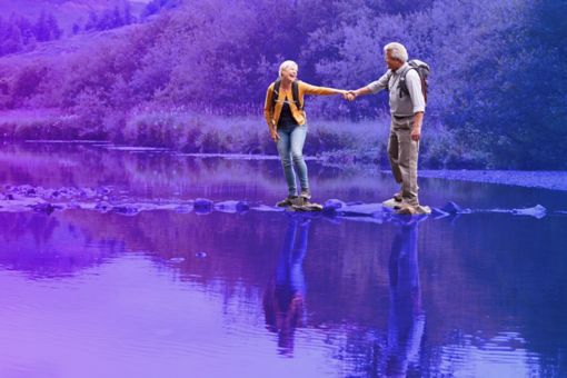 Couple crossing river whilst holding hands