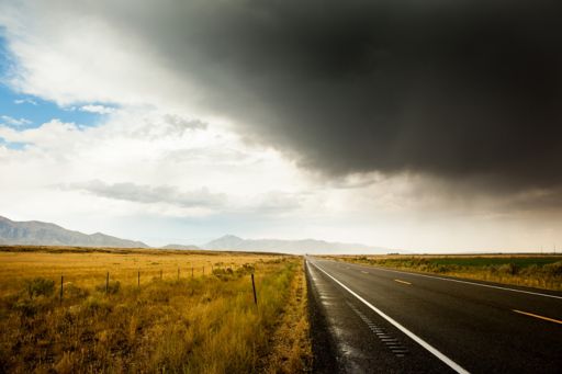 Dark clouds over an empty road and field