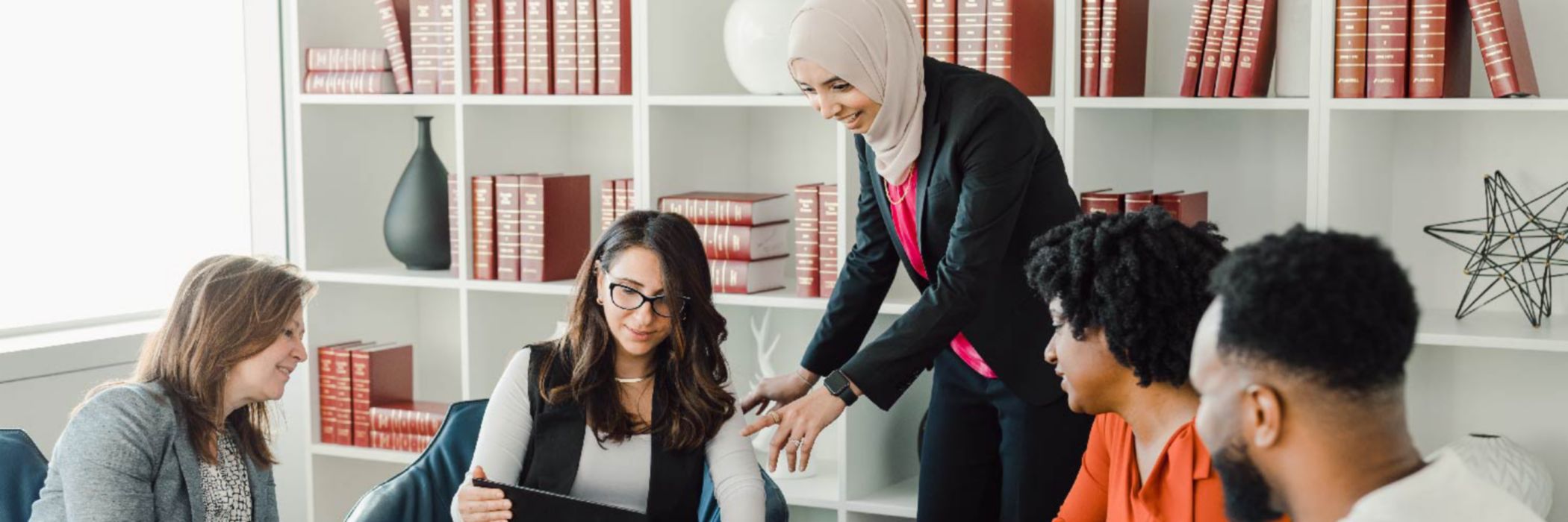 Four people in library talking around laptop