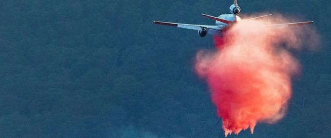 An aircraft waterbombs an out of control bushfire