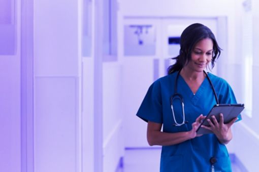 Female healthcare worker looking down interacting with a tablet