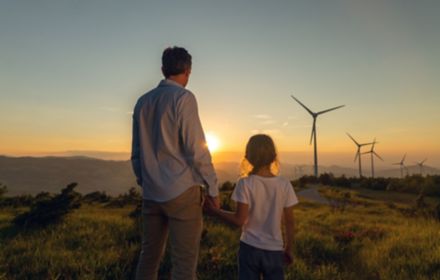 father and daughter looking at windturbines during sunset