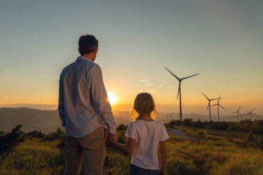 father and daughter looking at windturbines during sunset