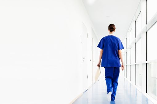 Young female doctor walking along corridor holding a clipboard