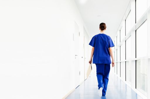 Young female doctor walking along corridor holding a clipboard