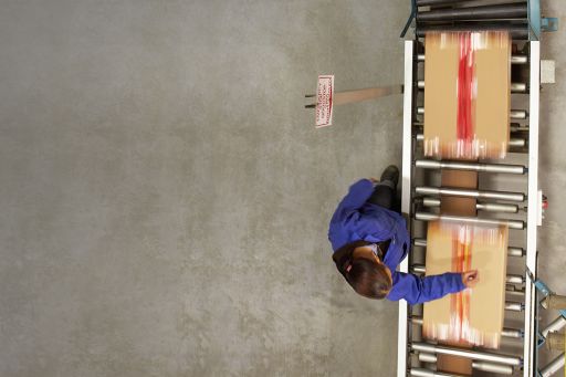 Female worker working next to a conveyor belt managing boxes