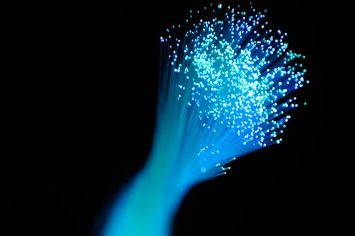 Bunch of light blue optic fibers against a black background.