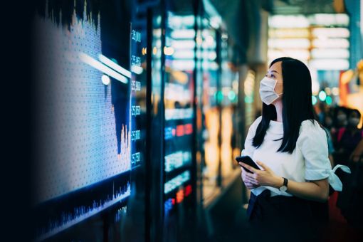 Businesswoman with protective face mask checking financial trading data