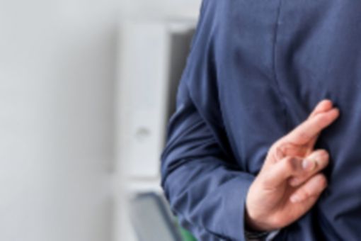 Person kreuzt Finger hinter dem Rücken